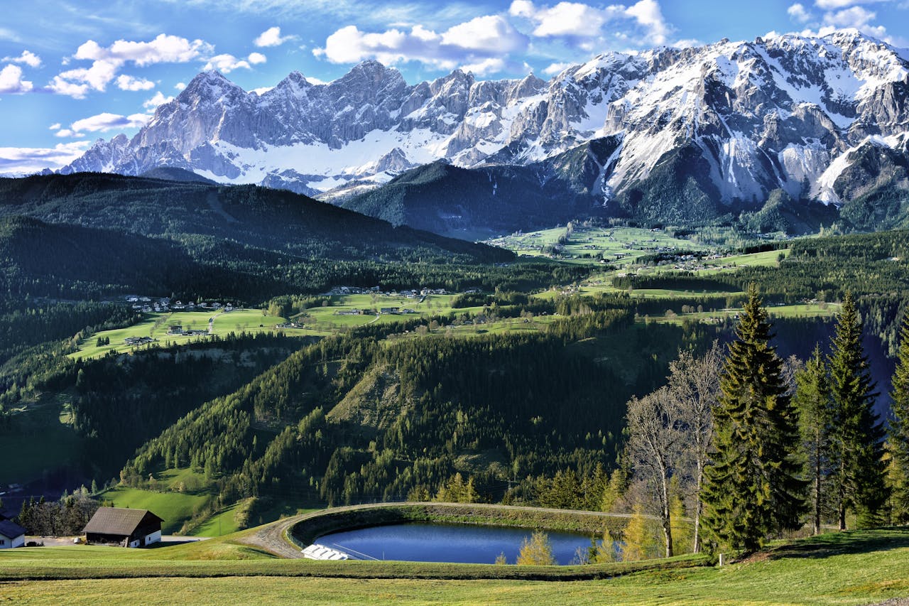 Stunning view of alpine mountains and green valleys under a bright blue sky. Perfect travel destination.