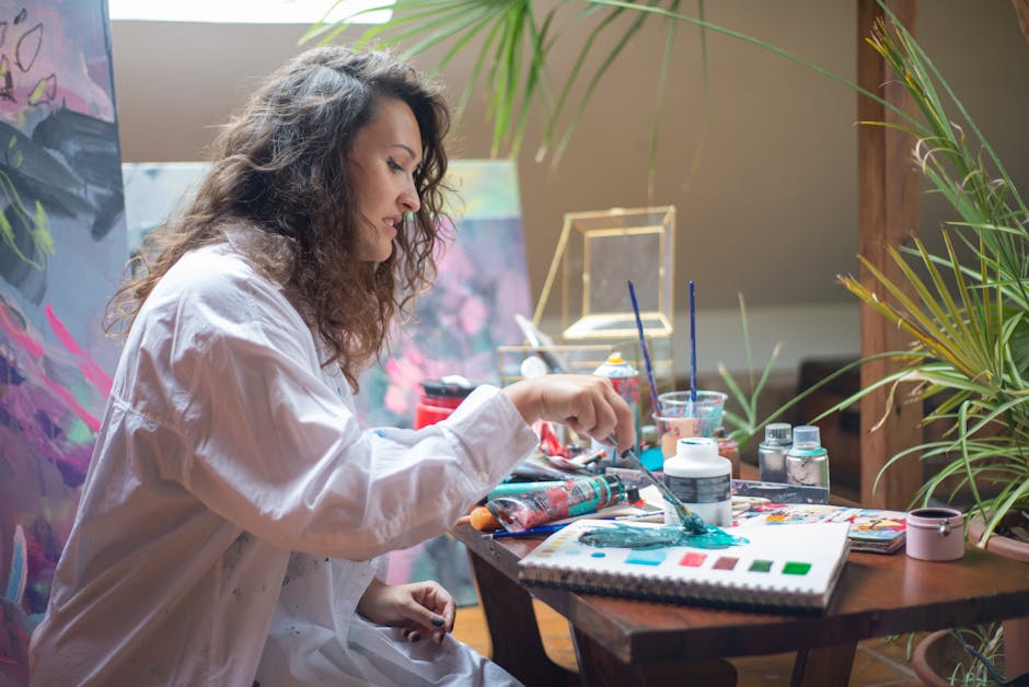 A woman artist painting with creativity and focus in her studio surrounded by artworks.